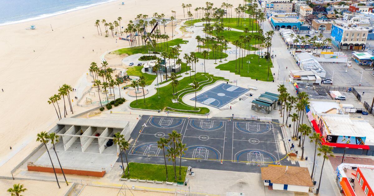 Bird's eye view of empty Venice Beach Boardwalk, basketball courts, palm trees, and skate park