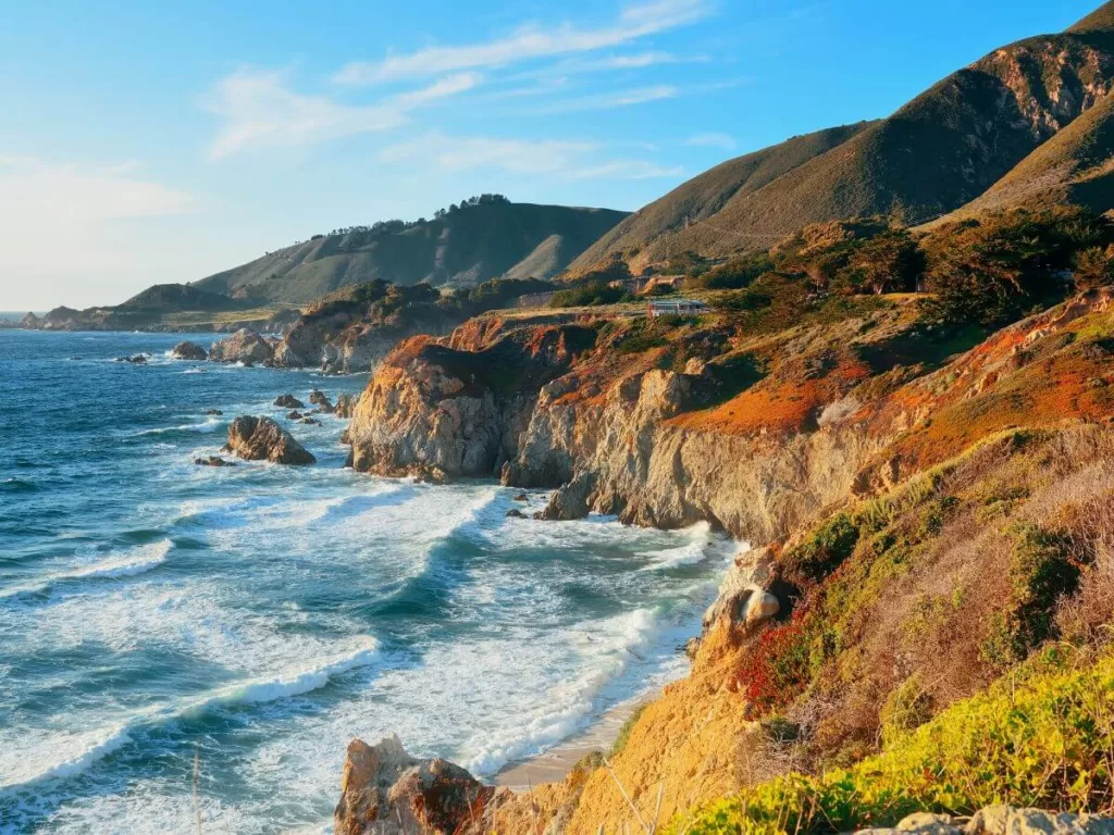 Breathtaking view of the rugged coastline of Big Sur, with crashing waves, steep cliffs, and verdant hills, showcasing one of the best stops when driving Big Sur.