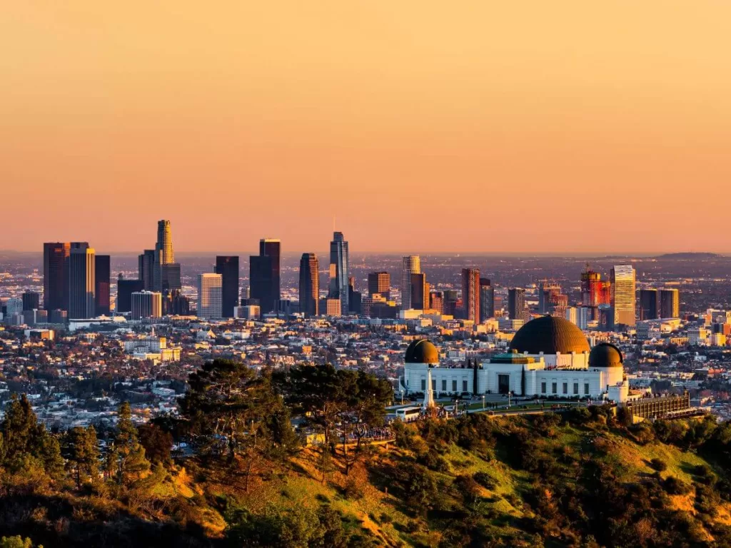 Golden hour view of Los Angeles with the Griffith Observatory in the foreground, overlooking the city's sprawling skyline, highlighting things to do in LA.