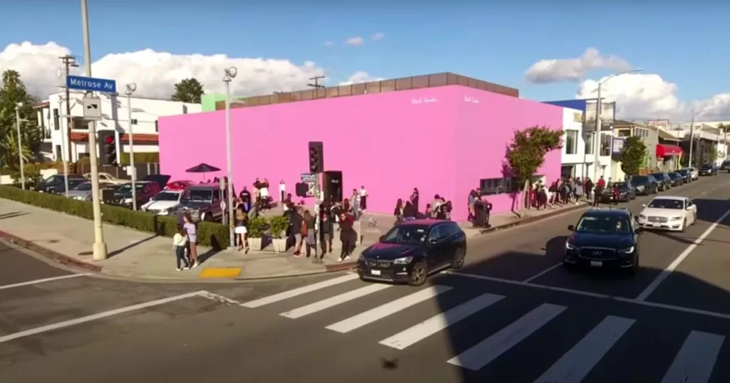 Vibrant scene on Melrose Avenue with a crowd of people near a striking pink building, showcasing LA's dynamic street culture and popular spots for shopping and dining.