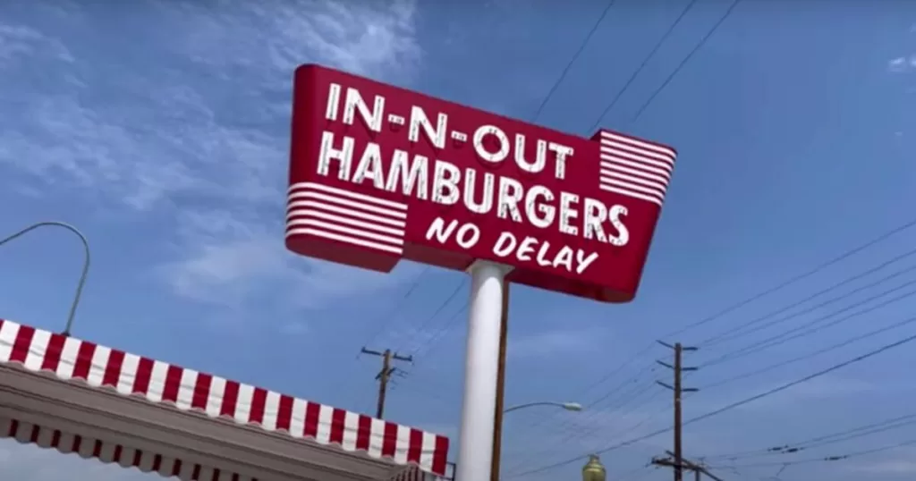 Iconic red and white In-N-Out Hamburgers sign against a clear blue sky, marking the location of The Original In-N-Out Burger Museum in California.