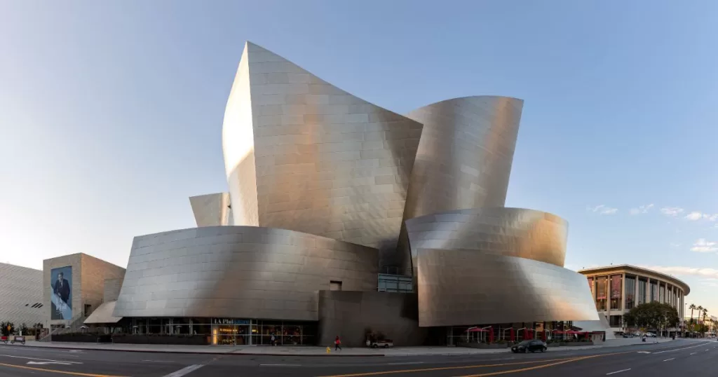 The Walt Disney Concert Hall in Los Angeles, featuring its modern, metallic architecture with fluid, curved lines, under a clear sky at dusk, a landmark destination for music and architecture enthusiasts.