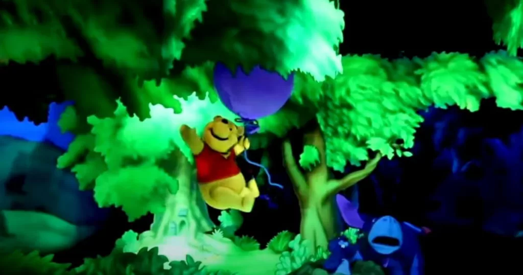 An animated bear character floating with a balloon among bright, whimsical trees in a vibrant theme park ride at Disneyland, Anaheim.