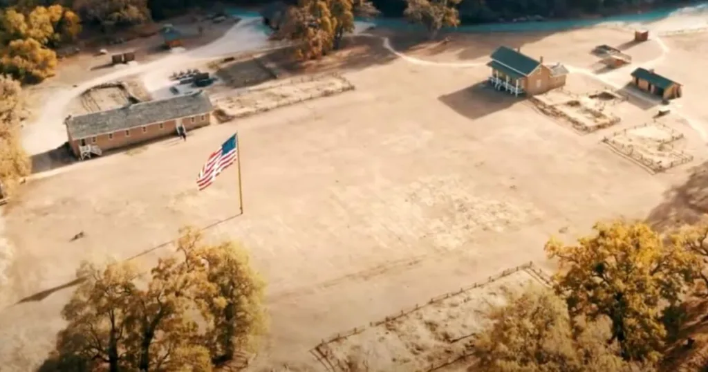 Aerial view of Fort Tejon State Historic Park, showing the barracks and other historical buildings with an American flag, a significant site among the best stops along I-5 California.