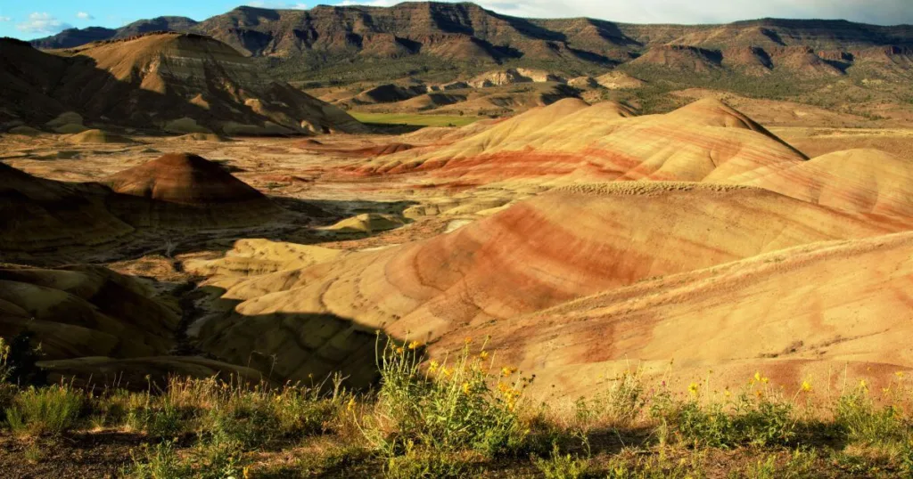 The Painted Hills, with their striking layers of yellow, gold, black, and red soil, under a vast sky.